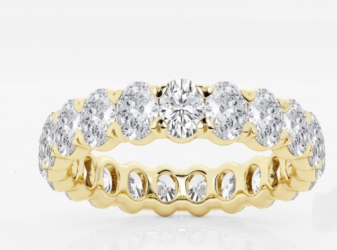 Oval-cut diamond eternity band with round brilliant center stone, in yellow gold