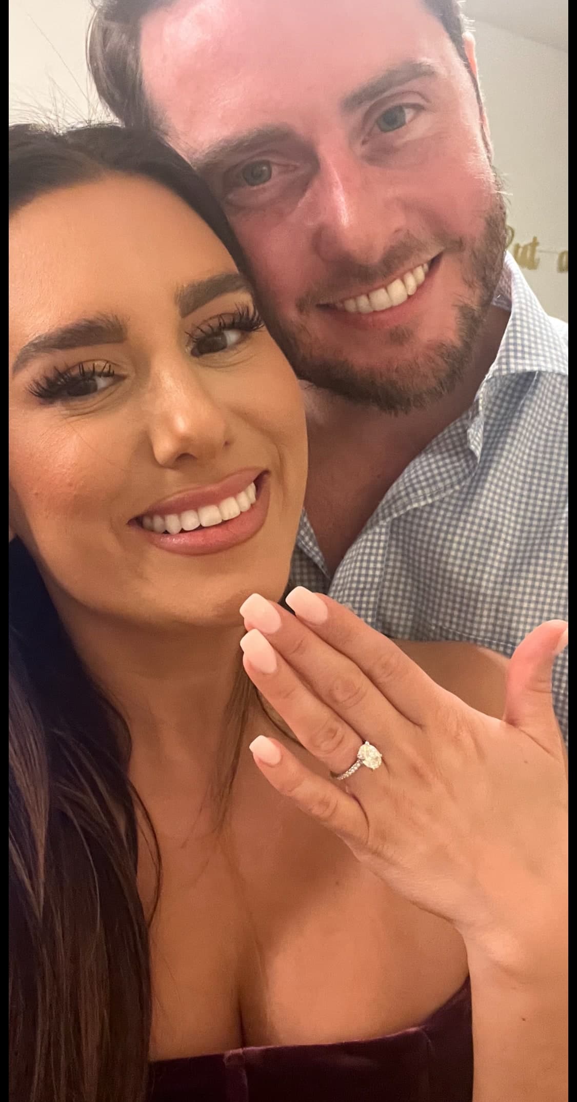Newly-engaged couple smiling — oval solitaire diamond ring on her finger