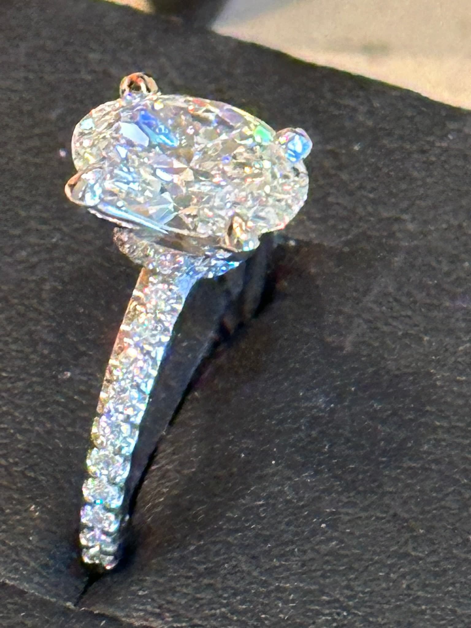 Oval brilliant solitaire with a pavé band on dark suede
